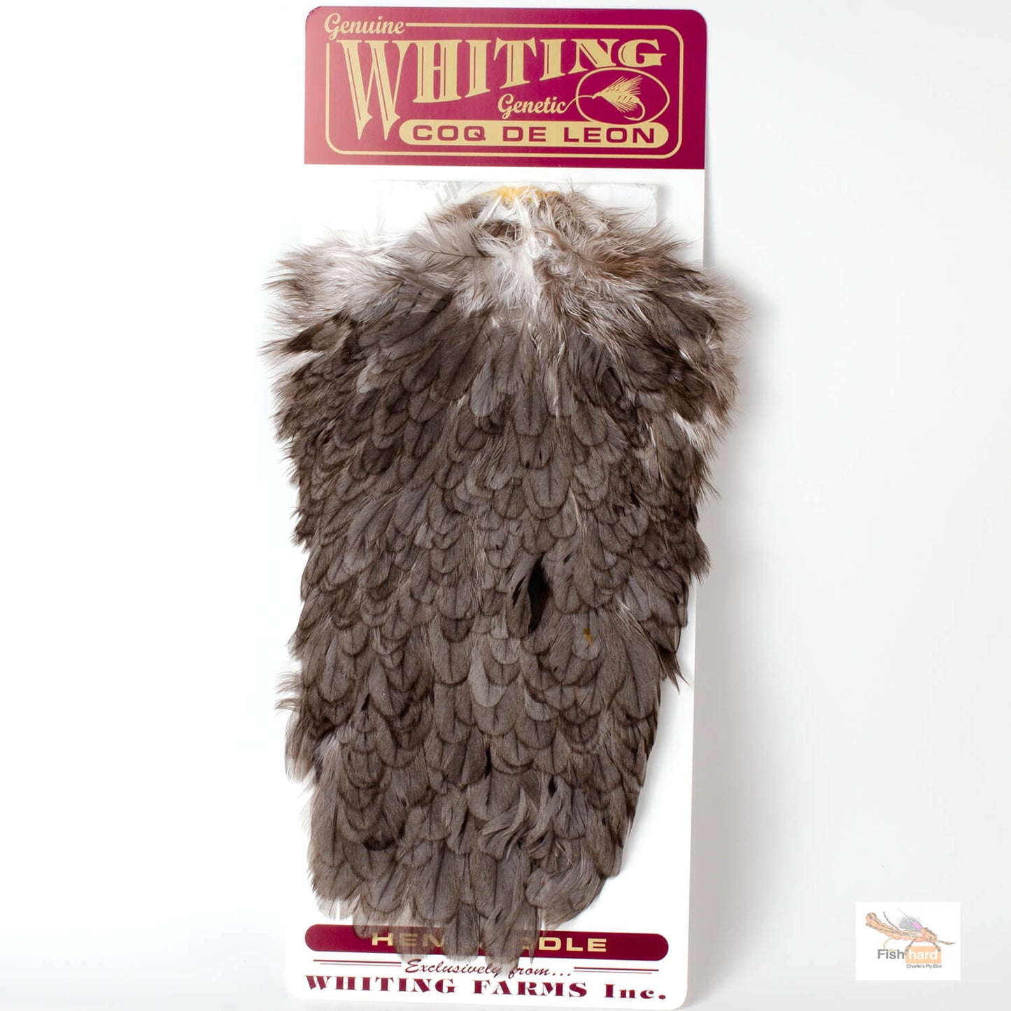 A packaged feather product labeled 'Genuine Whiting Genetic Coq de Leon' on a white backing card. The item appears to be a cluster of brown and gray feather-like plumes with a natural mottled pattern, photographed against a plain white background.