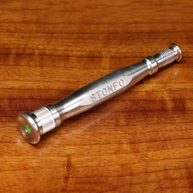 A silver metal hand tool engraved with the brand name 'STONFO' resting on a warm brown wooden surface.