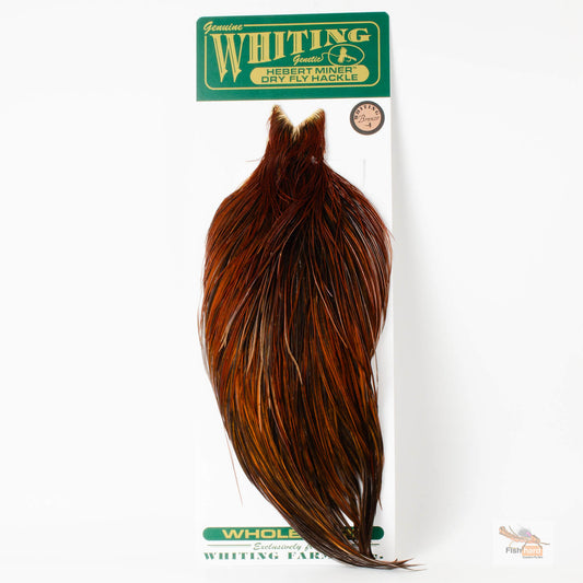 A packaged brown whole wing dry fly cape by Whiting Farms, shown hanging from its retail card packaging against a plain white background.